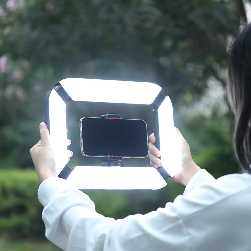 Person holding a Portable ring light with a smartphone, outdoors.