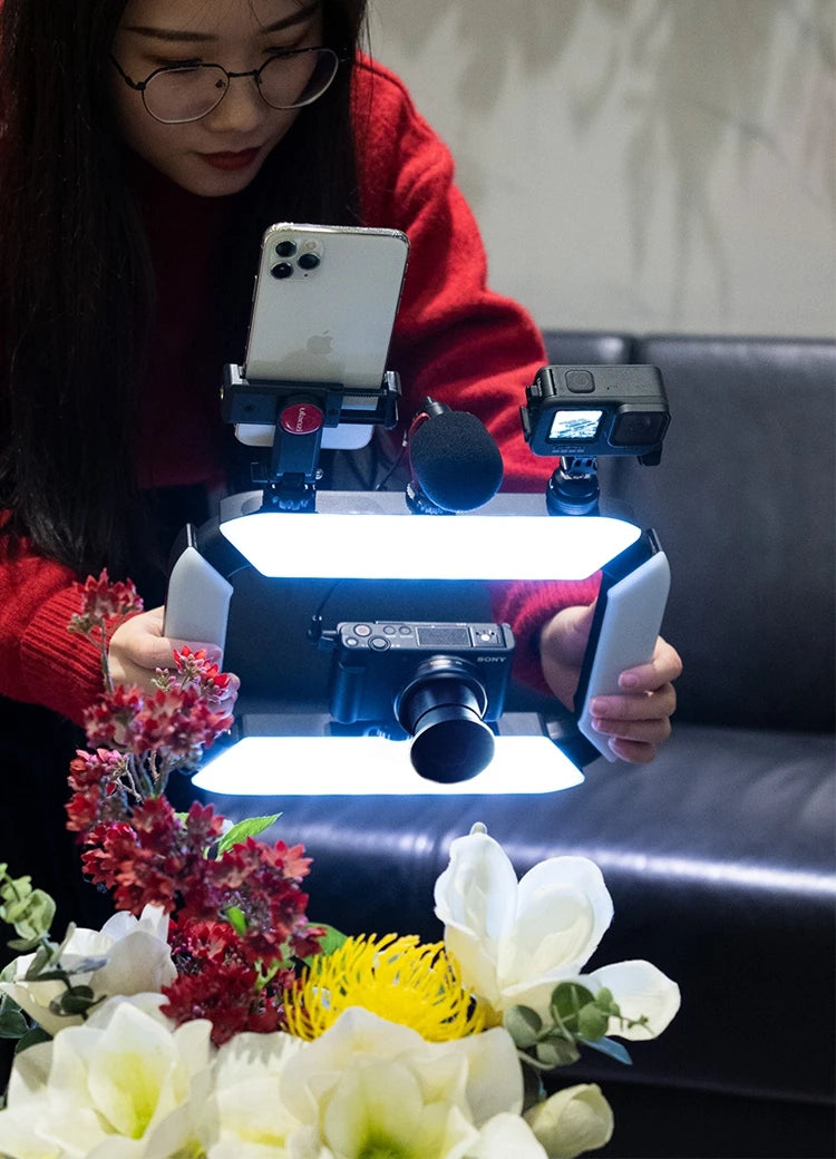 A woman using a camera rig with multiple devices, including a smartphone, microphone, action camera, and digital camera, to capture close-up shots of flowers.